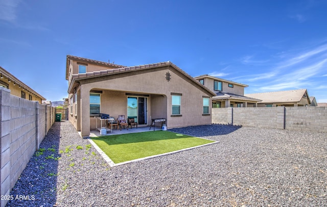 back of house with a patio area, stucco siding, a fenced backyard, and a yard