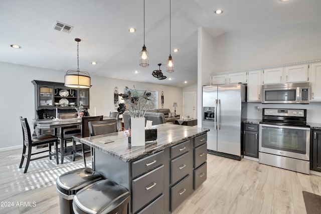 kitchen with decorative light fixtures, a center island, stainless steel appliances, and white cabinetry