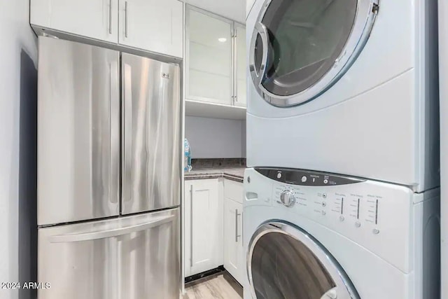 laundry room with stacked washer and clothes dryer and light hardwood / wood-style floors