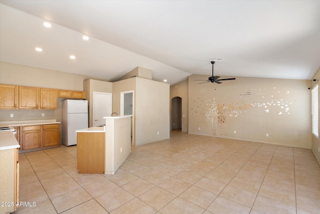 kitchen featuring freestanding refrigerator, open floor plan, light countertops, and arched walkways