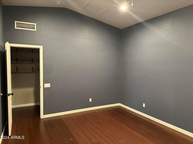 spare room with lofted ceiling and dark wood-type flooring