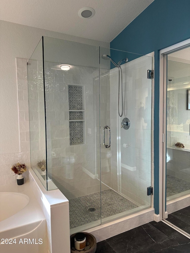 bathroom with a textured ceiling and shower with separate bathtub