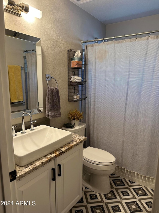 bathroom featuring vanity, toilet, a textured ceiling, and tile patterned floors