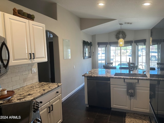 kitchen featuring light stone countertops, dishwasher, vaulted ceiling, and sink