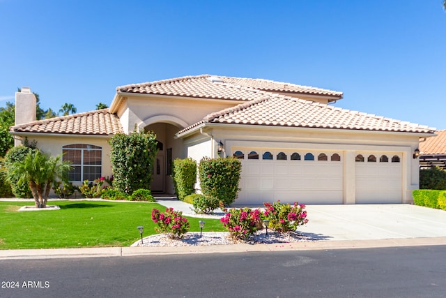 mediterranean / spanish-style house featuring a front yard and a garage