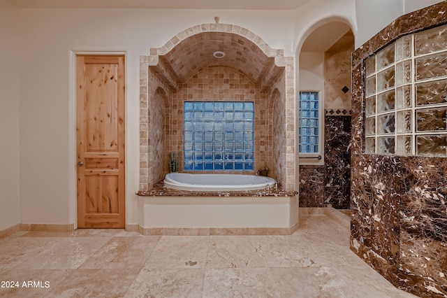 bathroom featuring tile walls, vaulted ceiling, and a tub