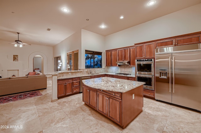 kitchen with light stone counters, stainless steel appliances, sink, and a kitchen island