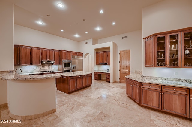 kitchen with kitchen peninsula, light stone counters, a center island, and stainless steel appliances