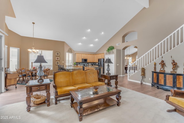 9702 E Naranja Ave, Mesa, AZ 85209 - living room with high vaulted ceiling, a chandelier, light wood finished floors, stairs, and arched walkways