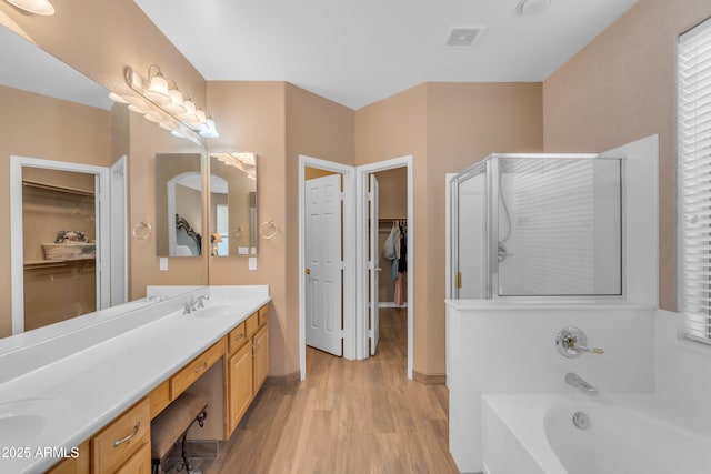 9702 E Naranja Ave, Mesa, AZ 85209 - bathroom with a walk in closet, double vanity, a garden tub, a stall shower, and wood finished floors