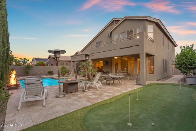 9702 E Naranja Ave, Mesa, AZ 85209 - back of house at dusk featuring a fire pit, a putting area, a patio area, and stucco siding