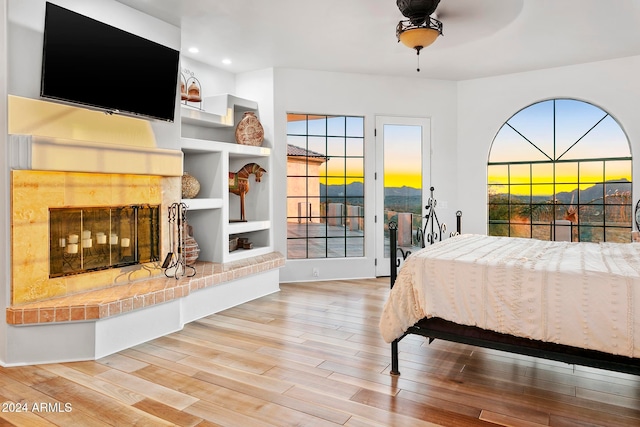 bedroom with hardwood / wood-style flooring, ceiling fan, access to exterior, and multiple windows