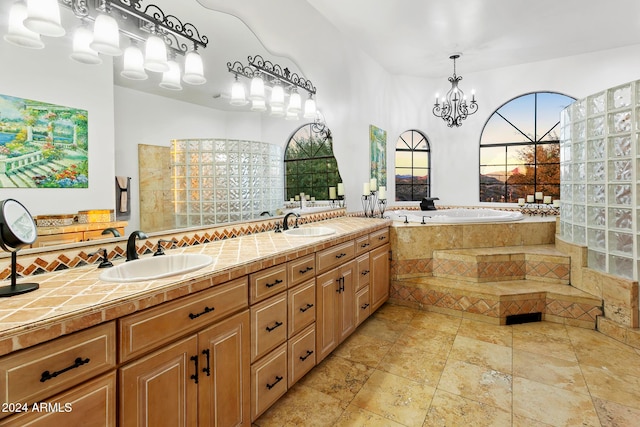 bathroom with tiled bath, vanity, and a notable chandelier