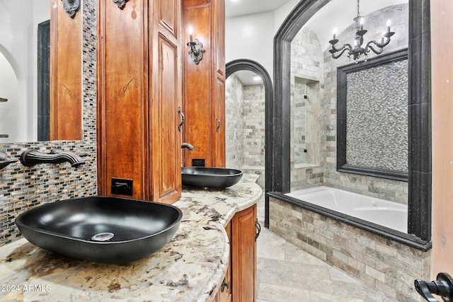 bathroom featuring tiled bath, tile patterned flooring, vanity, and a notable chandelier