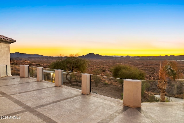 patio terrace at dusk featuring a mountain view