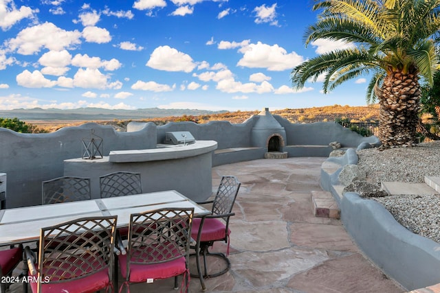 view of patio with a mountain view, exterior kitchen, and an outdoor fireplace