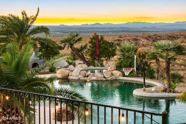 pool at dusk featuring a mountain view