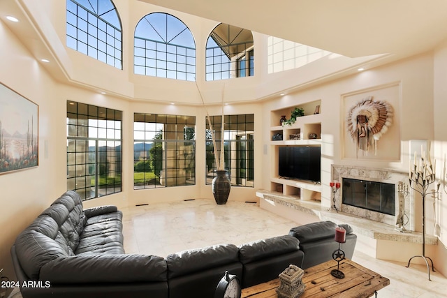 living room featuring built in features, a fireplace, and a high ceiling