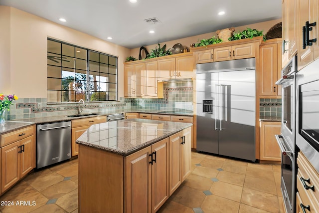 kitchen with appliances with stainless steel finishes, a center island, light stone counters, and backsplash