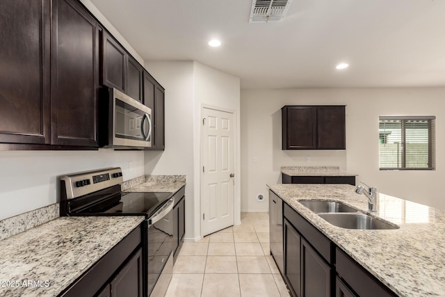 24627 W Ripple Rd, Buckeye, AZ 85326 - kitchen with stainless steel appliances, recessed lighting, light tile patterned flooring, light stone counters, and dark brown cabinetry