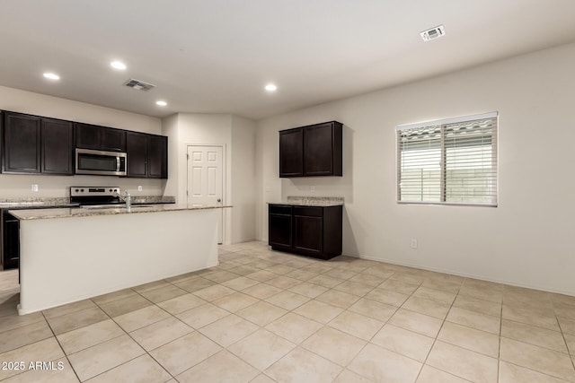 24627 W Ripple Rd, Buckeye, AZ 85326 - kitchen with stainless steel appliances, recessed lighting, light stone counters, light tile patterned floors, and an island with sink