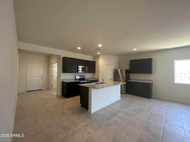 24627 W Ripple Rd, Buckeye, AZ 85326 - kitchen featuring stainless steel appliances, recessed lighting, light stone counters, light tile patterned flooring, and a center island with sink