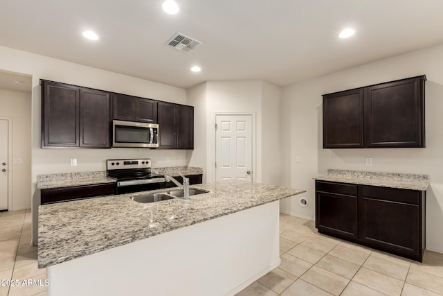 24627 W Ripple Rd, Buckeye, AZ 85326 - kitchen featuring stainless steel appliances, light tile patterned floors, dark brown cabinets, recessed lighting, and light stone counters