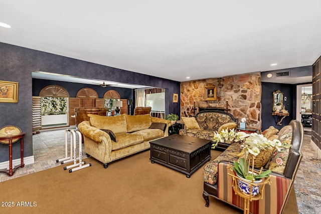 carpeted living area featuring a stone fireplace and visible vents