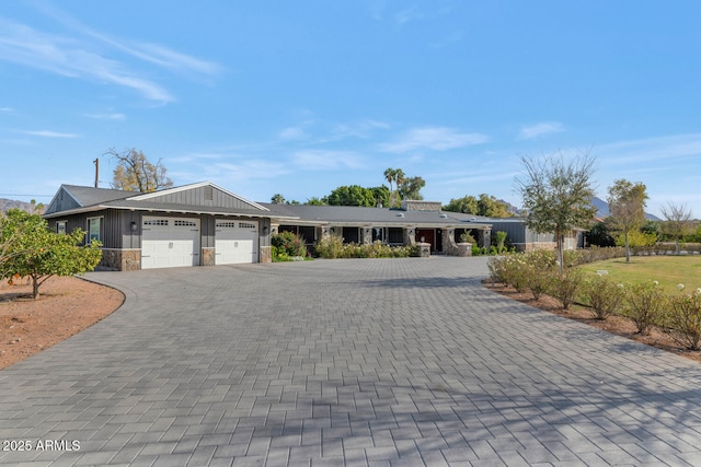 view of front of property with an attached garage, stone siding, and decorative driveway