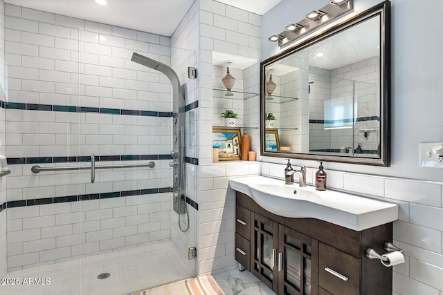 full bath with marble finish floor, a shower stall, tile walls, and vanity