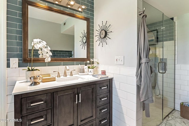 bathroom with marble finish floor, a wainscoted wall, tile walls, vanity, and a shower stall