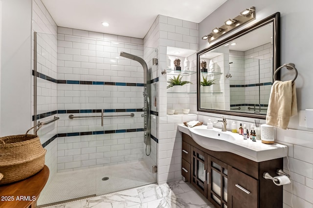 bathroom featuring tile walls, marble finish floor, a shower stall, and vanity