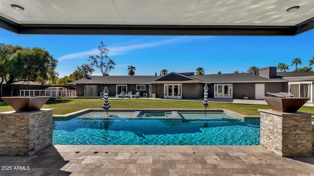 outdoor pool with a yard, a patio, and french doors