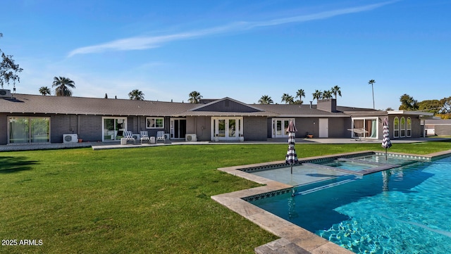 rear view of house featuring french doors, brick siding, a patio, a lawn, and an outdoor pool