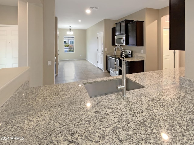 kitchen with visible vents, appliances with stainless steel finishes, light stone counters, tile patterned floors, and a sink