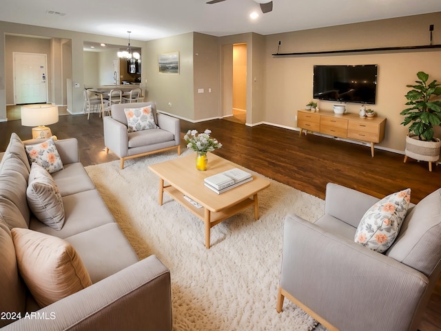 living room with ceiling fan with notable chandelier and dark hardwood / wood-style floors