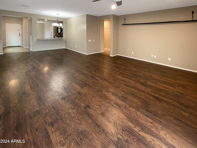 unfurnished room featuring wood finished floors, visible vents, baseboards, and ceiling fan with notable chandelier