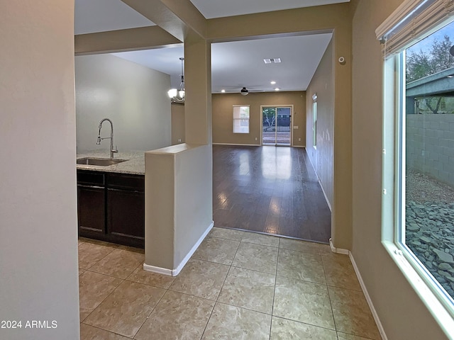 hall featuring visible vents, a sink, baseboards, and light tile patterned floors