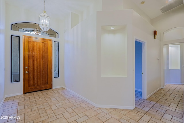 entryway with baseboards, a high ceiling, and a notable chandelier