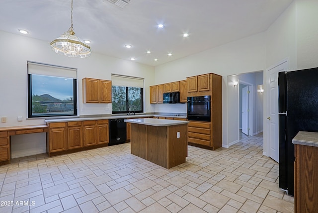 kitchen with black appliances, built in study area, a center island, and brown cabinets