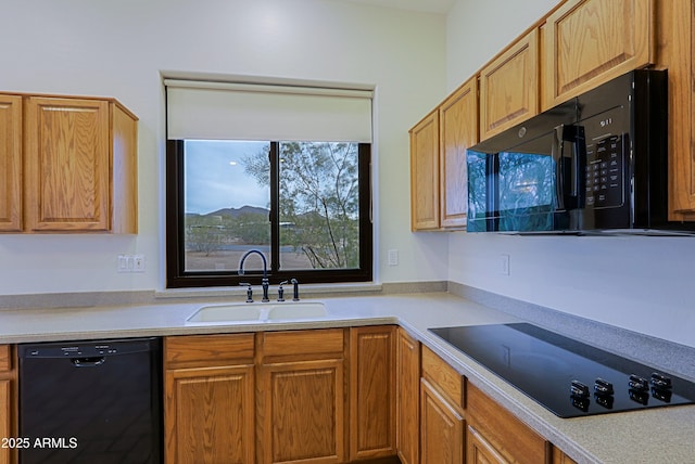 kitchen with black appliances, a sink, and light countertops