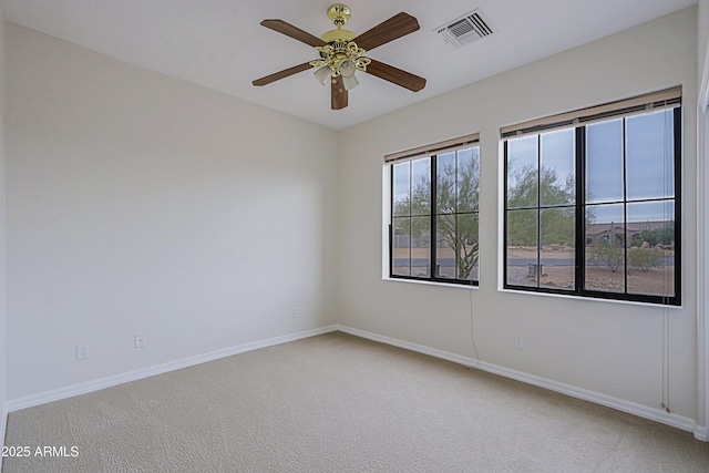 carpeted spare room featuring visible vents, ceiling fan, and baseboards