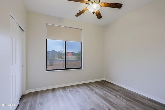 unfurnished bedroom featuring a ceiling fan, a closet, baseboards, and wood finished floors