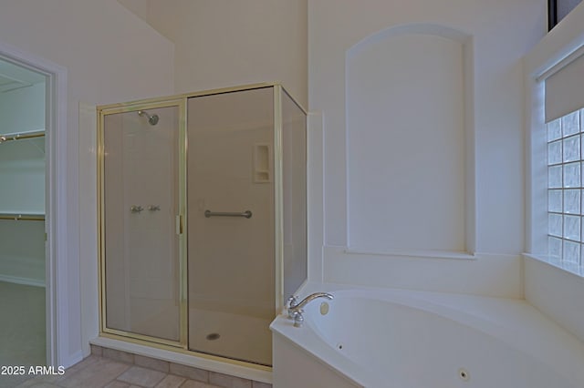 bathroom featuring a stall shower, a tub with jets, and a walk in closet