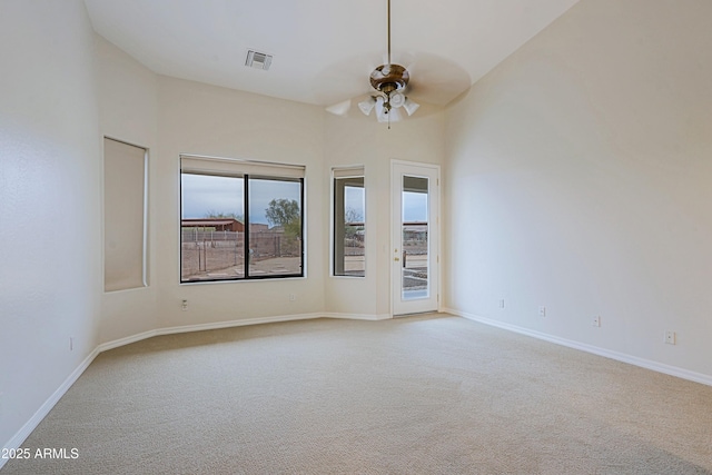 spare room with carpet floors, visible vents, ceiling fan, and baseboards