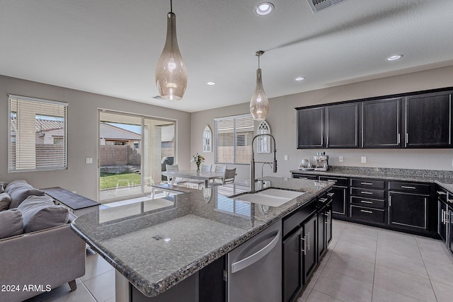 kitchen with sink, stainless steel dishwasher, pendant lighting, stone countertops, and a center island with sink