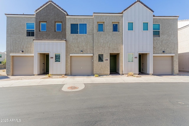 townhome / multi-family property featuring board and batten siding, a tile roof, and stucco siding