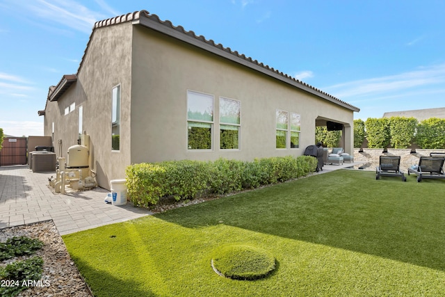 rear view of property featuring a yard, central AC, and a patio area