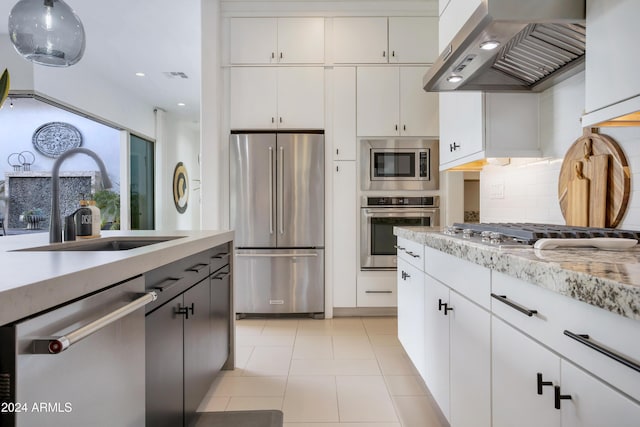 kitchen featuring tasteful backsplash, stainless steel appliances, sink, wall chimney range hood, and white cabinets