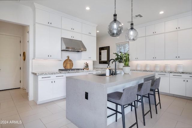 kitchen featuring white cabinetry, sink, a kitchen island with sink, range hood, and decorative backsplash